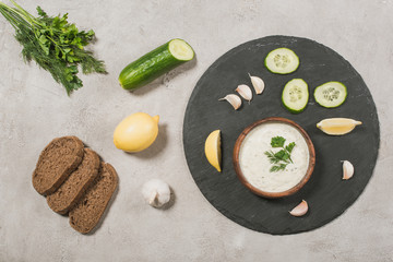 Top view of tzatziki sauce with ingredients and bread on stone background