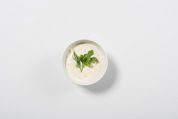 Top view of tasty tzatziki sauce with greenery on white background