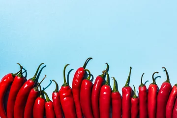 Fotobehang Top view of spicy red chili peppers on blue background © LIGHTFIELD STUDIOS