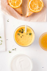 Indian lassi mango drink next to yogurt and sandwiches on a white concrete background