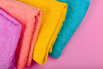 Multi-colored towels on a pink background. Pink, beige, yellow and blue flower towels. Place for writing. House order.