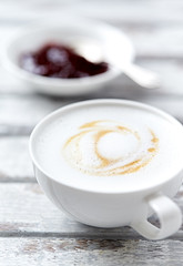 Cup of coffee with milk on white wooden background. Close up. 