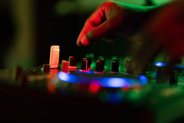 club dj plays music on stage in nightclub.Hand of disc jockey adjusting sound track volume...