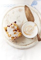 Coffee with milk, a piece of yeast cake on bright background. Top view. 