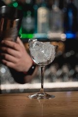 bar accessories shaker and full of ice cocktail glass on a bar background