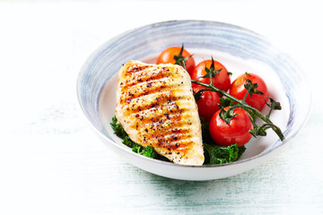 Grilled Chicken Breast with roasted Cherry Tomatoes. Bright wooden background. Close up. Copy space. 