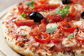 Pizza with mozzarella cheese, cherry tomatoes, black olives and fresh oregano. Home made food. Concept for a tasty and hearty meal. Close up. 