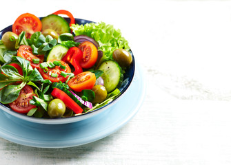 Tasty salad with green Olives, cherry Tomatoes and Cucumber. Healthy Snack Idea. Bright wooden background. 