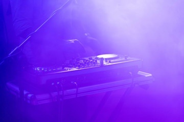 club dj plays music on stage in nightclub.Hand of disc jockey adjusting sound track volume level.Professional audio equipment on music festival