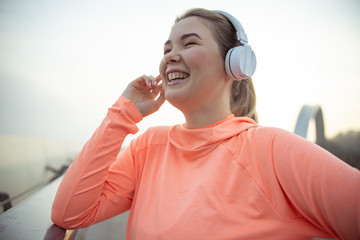 Cheerful young woman listening to music outdoors