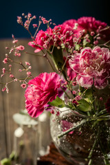 Bouquet of pink carnation in glass vase on old wooden background. Mothers day, birthday greeting card.