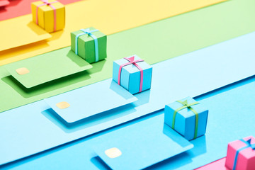 multicolored empty credit cards and gift boxes on rainbow background