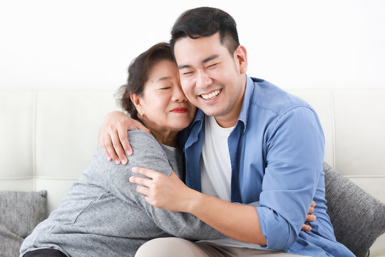 Asian senior grand mother with son happy and smile on the sofa in living room love family concept
