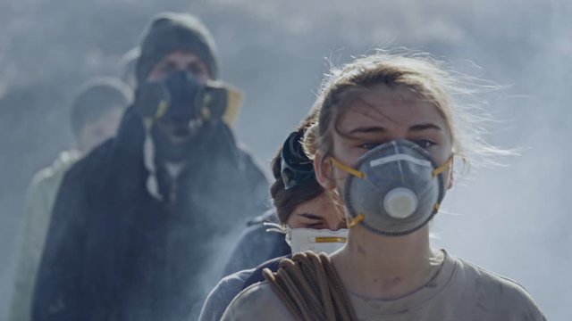 Portrait of people in gas mask standing in clouds of toxic smoke.