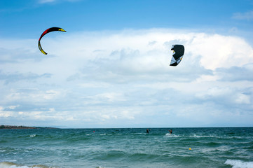 Kite surf ride his hydrofoil kite through surfing waves on sea.  Kitesurfers ride kites on Black Sea at sandy Beach In Bulgaria, Sozopol on sunny day at sunset on blue sky and clouds background.