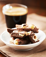 Chocolate with Nuts and coffee in glass cup in background. Close up. 
