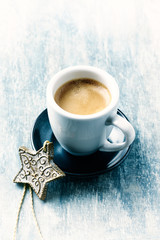 Wooden Christmas Star and a cup of coffee on bright wooden background. Close up. 