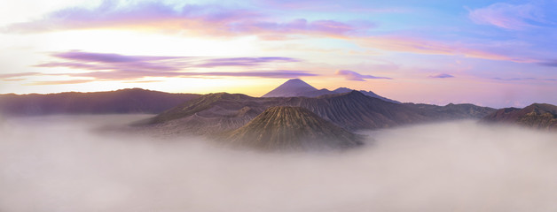 Fototapeta na wymiar View from above, stunning panoramic view of the Mount Semeru, Mount bromo and the Mount Batok surrounded by clouds during a beautiful sunrise. East Java, Indonesia.