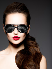 Fashion portrait of  woman wearing black sunglasses with diamonds and red lips