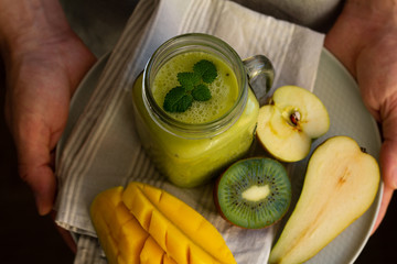 smoothies in a glass and fruits in men's hands