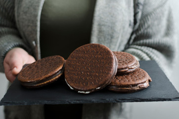 Closeup of chocolate biscuts on the slate board.Woman holding tray with chocolate cookies