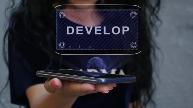 Unrecognizable curly brunette woman showing HUD hologram with text Develop. Girl uses technology of the future on a mobile screen