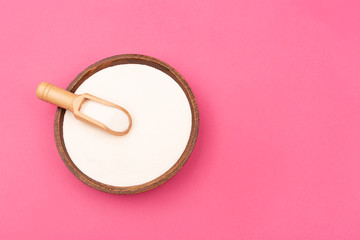 Collagen powder in wood plate on magenta background. Flatlay, top view. Copy space for your text.