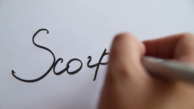 Hand writing Scorpius on white paper. Astrology concept