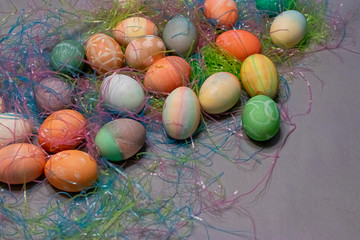 colorful dyed easter eggs gathered on a table with easter grass