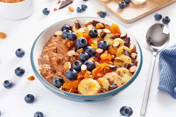 chocolate oatmeal porridge with blueberry, nuts, banana, dried apricot for healthy breakfast