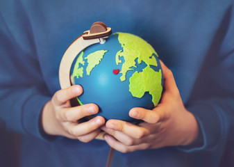 Cropped shot little boy holding the earth in his hands. Hands holding globe with red heart on map, Earth day on April 22 , Green World environment day concept