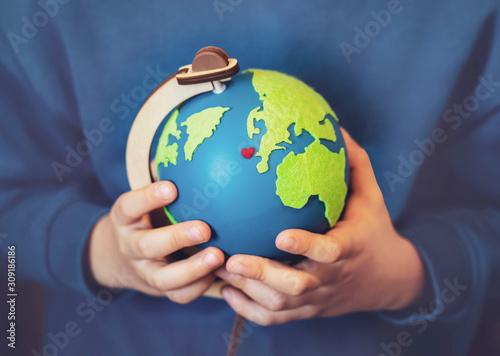 Cropped shot little boy holding the earth in his hands. Hands holding globe with red heart on map, Earth day on April 22 , Green World environment day concept
