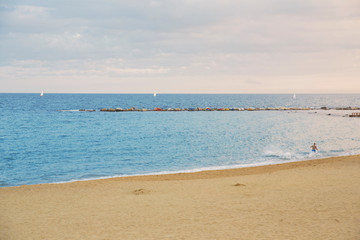 View of Barcelona beach, in the Barceloneta district, overlooking the Mediterranean Sea. The sky is dark and there are many waves.