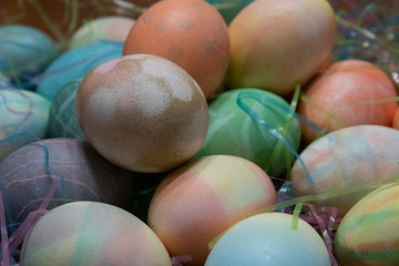 colorful dyed easter eggs gathered on a table with easter grass