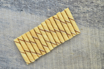 Vanilla waffle roll sticks lined up on wooden background