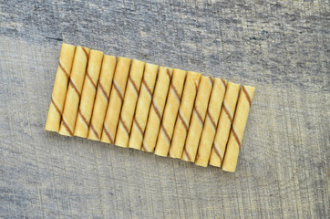 Vanilla waffle roll sticks lined up on wooden background