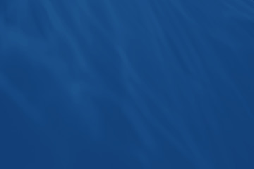Trendy blue colored low contrast abstract background with light and shadows caustic effect. Light passes through a glass. Water background. 2020 year color trend