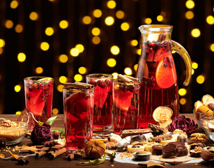 Christmas mulled wine or gluhwein with spices, chocolate sweets and orange slices on rustic table, traditional drink on winter holiday, christmas lights and decorations