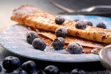Crepes with blueberries. Homemade pancakes, crepes on blue plate,