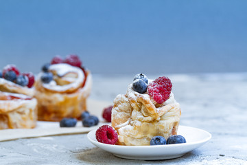 Delicious and beautiful berry rose puff pastries. Classic winter sweet dessert on blue background. French new year dessert.