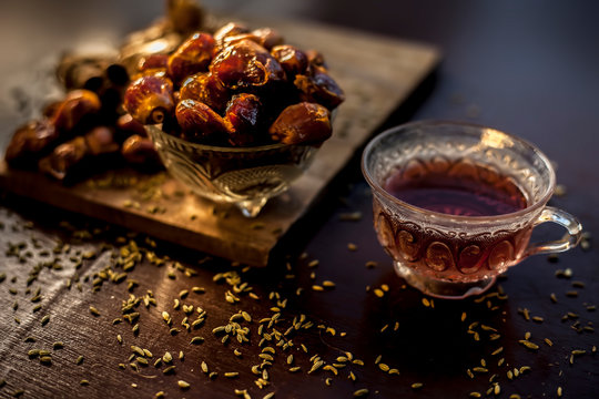 Dates tea in transparent glass cup along with some fennel seeds, cinnamon sticks and ginger well mixed and put together in tea.The horizontal well lit upshot of dates tea in a transparent glass cup.