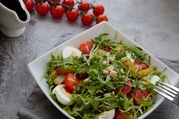 Healthy vegetable salad with cherry tomatoes, arugula, egg, caramelized pear and nuts. Vegetable salad with sauce. Salad with dressing. Salad with an egg. Salad with pear. Vegetarian