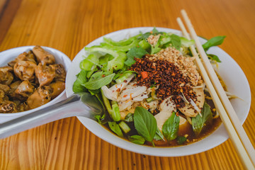 Chicken noodles soup in bowl at noodle shop street .	