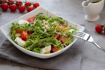 Healthy vegetable salad with cherry tomatoes, arugula, egg, caramelized pear and nuts. Vegetable salad with sauce. Salad with dressing. Salad with an egg. Salad with pear. Vegetarian