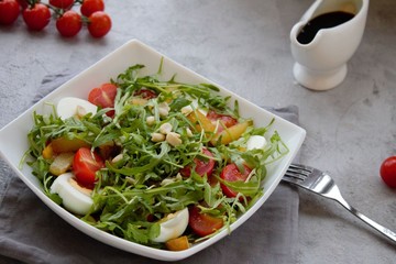 Healthy vegetable salad with cherry tomatoes, arugula, egg, caramelized pear and nuts. Vegetable salad with sauce. Salad with dressing. Salad with an egg. Salad with pear. Vegetarian