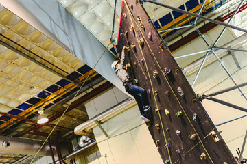Boy climbing a climbing wall to the top to overcome his fears.