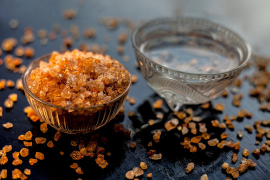 Gond katara/Gond Katira/ Tragacanth Gum or edible gum in a glass bowl along with some water in another bowl for relief in back pain. On a black glossy surface with some spread gond crystals.