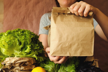 Organic vegetables in eco bag in market. Woman seller giving craft paper bag with products in organic food store.  Healthy nutrition, Zero Waste, Lifestyle. Mock up blank blank template for, design