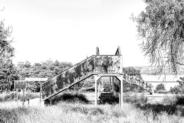 Rusted, old pedestrian railway bridge, in Brandfort. Monochrome