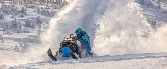 Schilderijen op glas Pro snowmobiler makes a turn and lets a flurry of snow spray from under the caterpillar. sports snowmobile in the mountains. bright skidoo motorbike and suit without brands. Winter fun moto extreme © Wlad Go